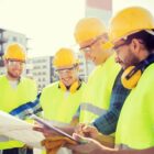 A team of contractors reviewing blueprints at a construction site.